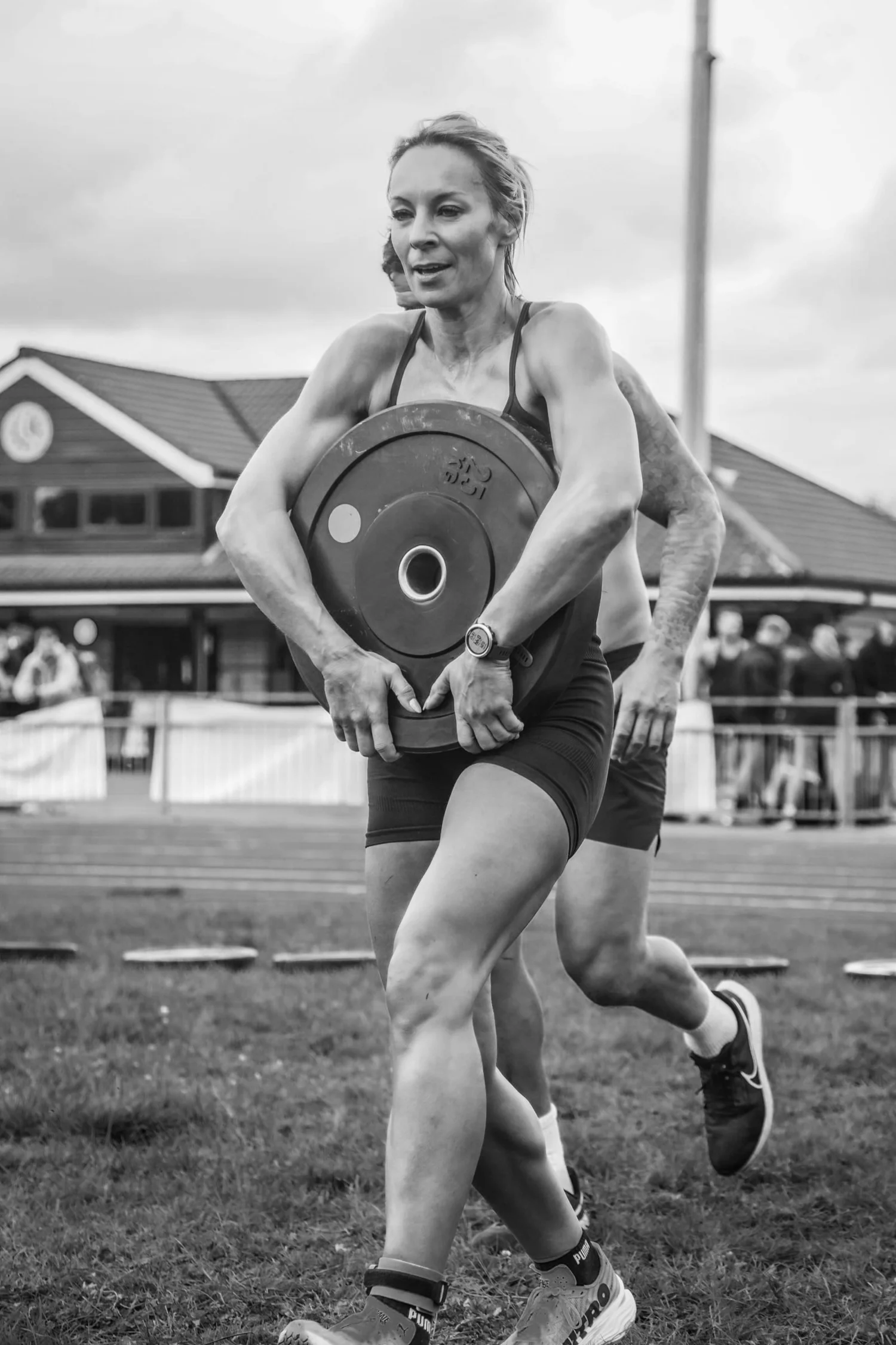 Atleet wat 'n gewigplaat aan die voorkant van die lyf dra in die Front Carry Labour