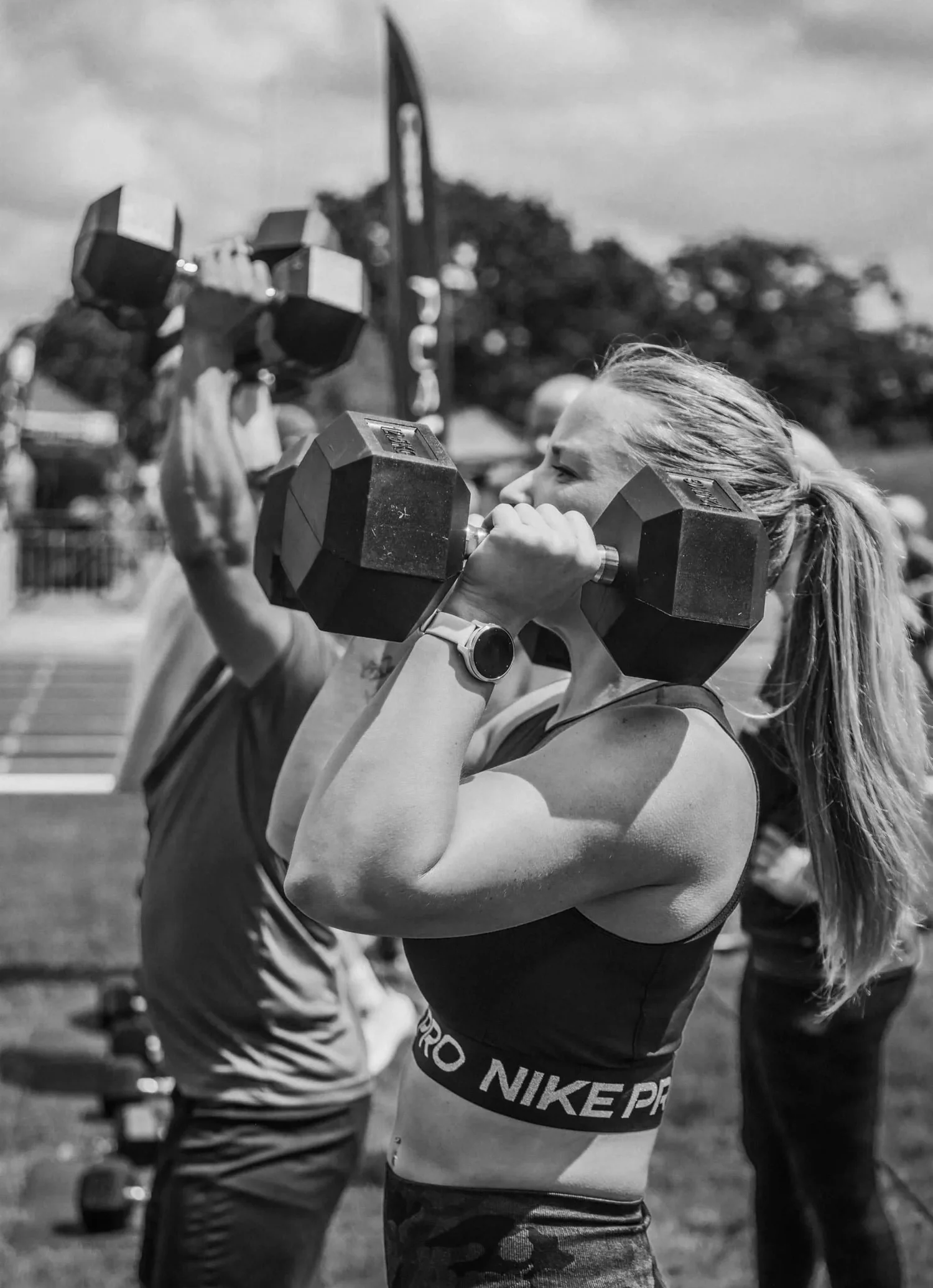 Atleet druk twee handgewigte oorhoofse in die Push Press Labour