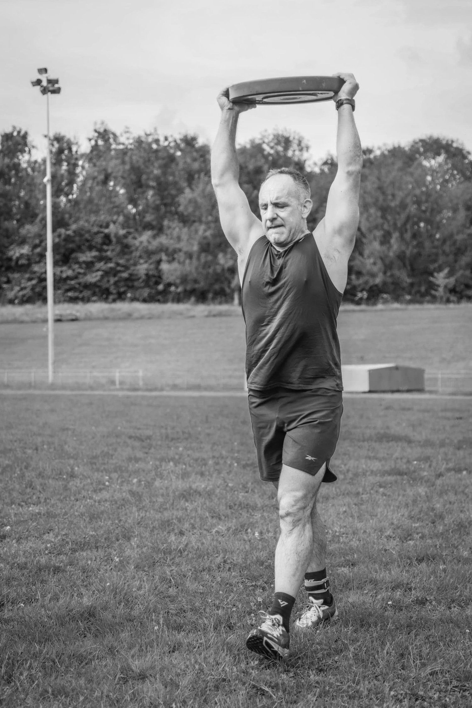 Atleet wat 'n gewigplaat oorhoofse dra in die Oorhoofse Dra Arbeid