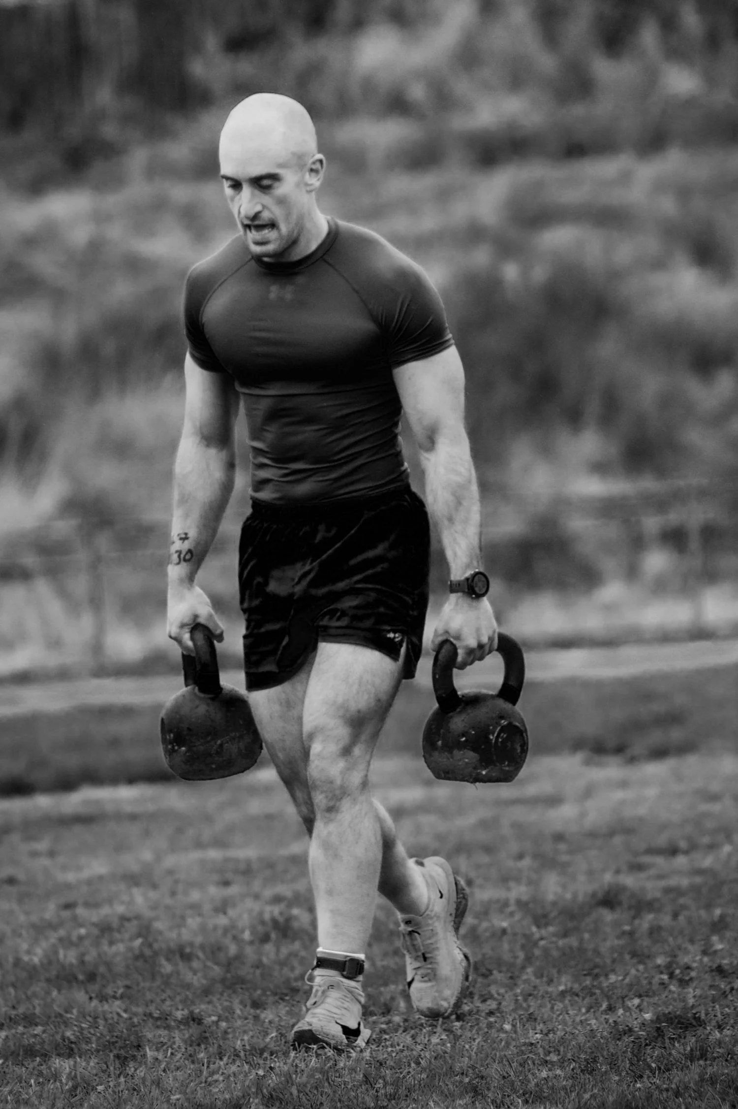 Atleet wat twee kettlebells dra in die 30m-baan in die Farmers Carry Labour
